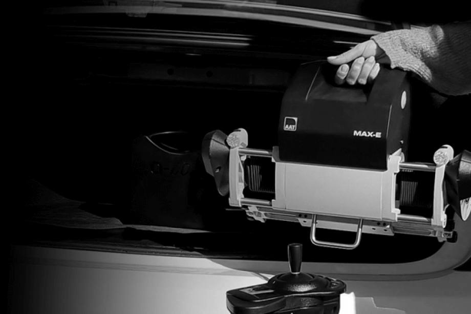 The picture shows a section of a passenger car trunk. A woman's hand easily lifts the drive unit into the trunk with just one hand. 