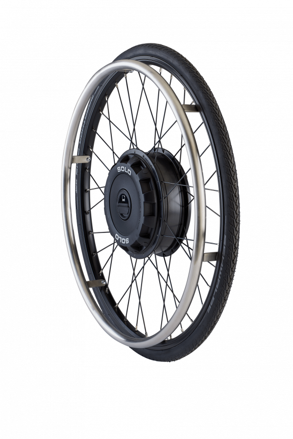 The picture shows the exposed wheel of the auxiliary drive SOLO on a white background. You can see the black wheel hub drive, with black spokes and a black wheelchair tire.